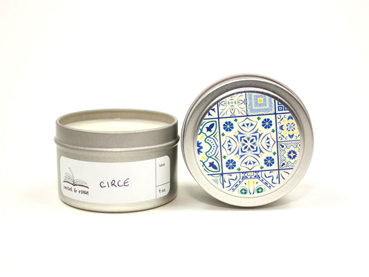 Onset & Rime lemon, cypress scented candle called "Circe" in a 4 oz silver tin. The circular label on top is white with a dark blue Greek tile pattern. The scent name is handwritten on a white rectangular label on the side of the tin.